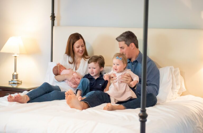 A family of 5 playing on a bed together