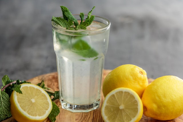 A glass of lemonade with lemons around it