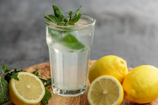 A glass of lemonade with lemons around it