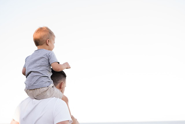 A little kid on top of their dad's shoulders