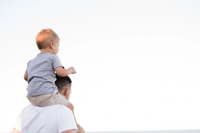A little kid on top of their dad's shoulders