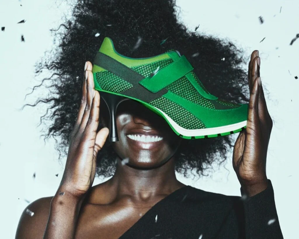 Someone holding a sneaker that has a high heel attached to it